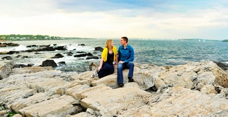 couple sitting on rocks at fort williams park in cape elizabeth, maine